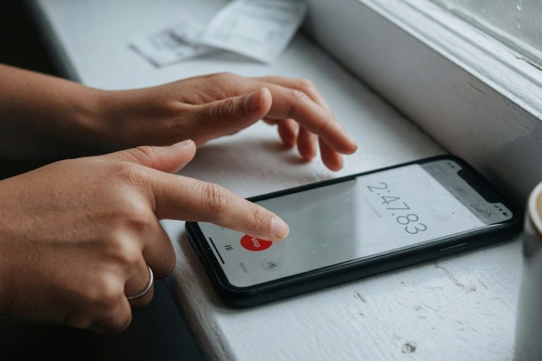 Mains actionnant un chronomètre sur smartphone près d'une fenêtre