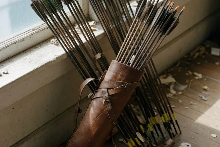 Quiver en cuir rempli de flèches sur parquet clair sous lumière naturelle douce